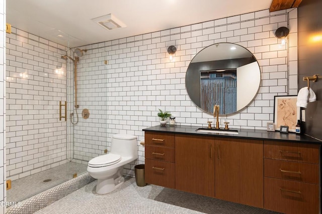 bathroom featuring toilet, decorative backsplash, a shower with door, vanity, and tile walls