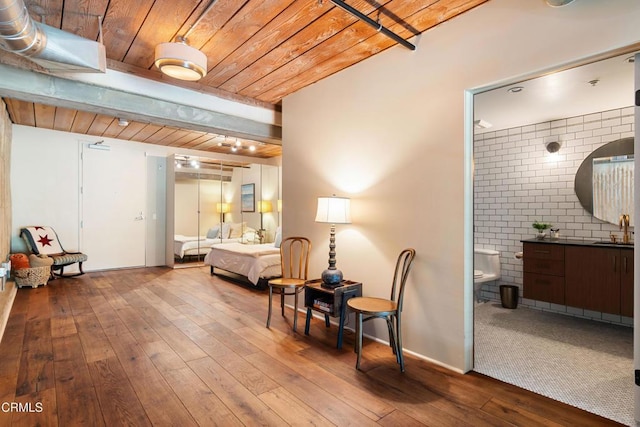 bedroom featuring light hardwood / wood-style flooring, sink, brick wall, and ensuite bath