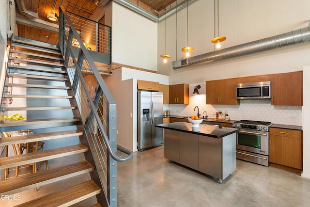 kitchen with hanging light fixtures, stainless steel appliances, a high ceiling, tasteful backsplash, and a kitchen island