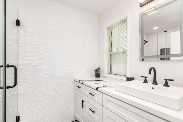 bathroom featuring a shower with shower door, tile walls, vanity, and tasteful backsplash