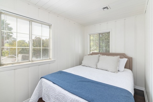 bedroom with dark wood-type flooring, wooden ceiling, and multiple windows