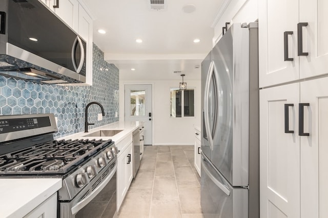 kitchen featuring decorative backsplash, white cabinets, appliances with stainless steel finishes, and sink