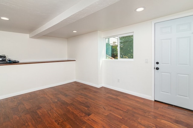 interior space with dark hardwood / wood-style flooring and beamed ceiling