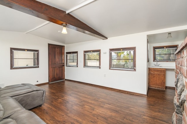 unfurnished living room with dark wood-type flooring, vaulted ceiling with beams, and sink