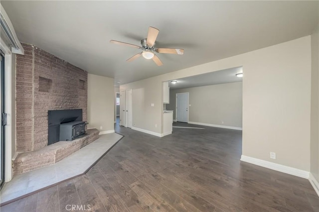 unfurnished living room with ceiling fan, dark wood-type flooring, and a wood stove