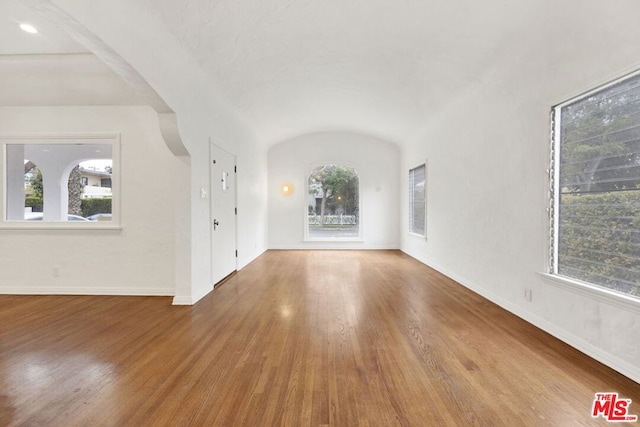 unfurnished living room with plenty of natural light, lofted ceiling, and hardwood / wood-style floors