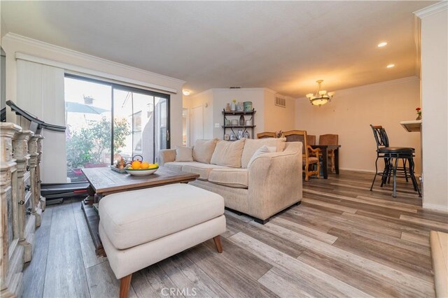 living room featuring an inviting chandelier, ornamental molding, and light hardwood / wood-style flooring