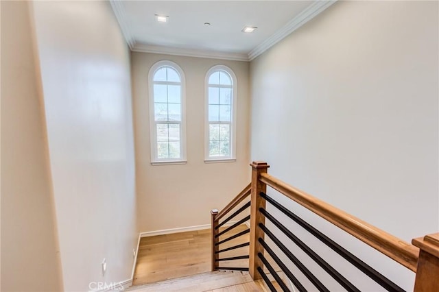 stairs with wood-type flooring and crown molding