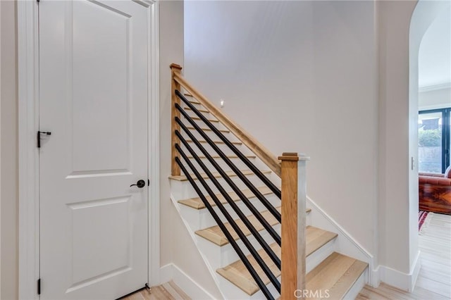 stairs featuring ornamental molding and hardwood / wood-style flooring