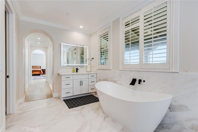 bathroom with vanity, tile walls, ornamental molding, and a bath