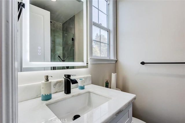 bathroom featuring a shower with door and vanity