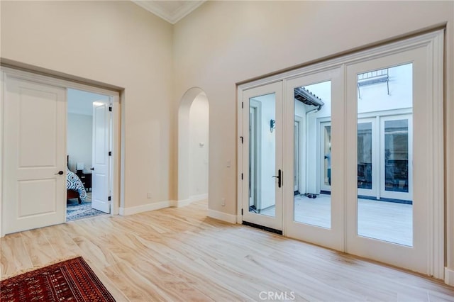 entryway with light hardwood / wood-style floors, french doors, and crown molding