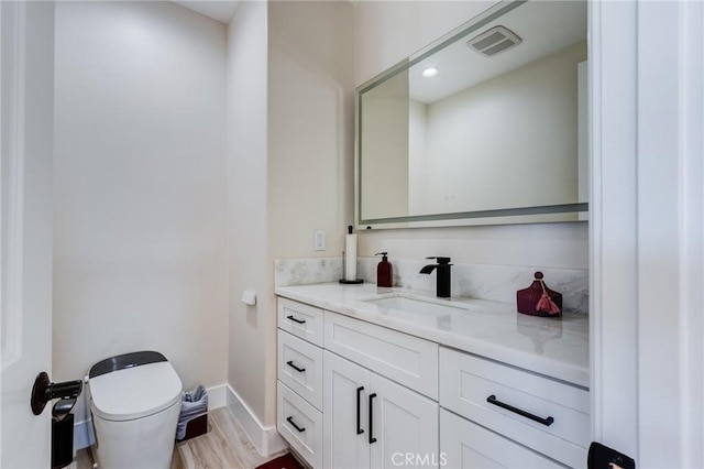 bathroom featuring toilet, vanity, and hardwood / wood-style flooring