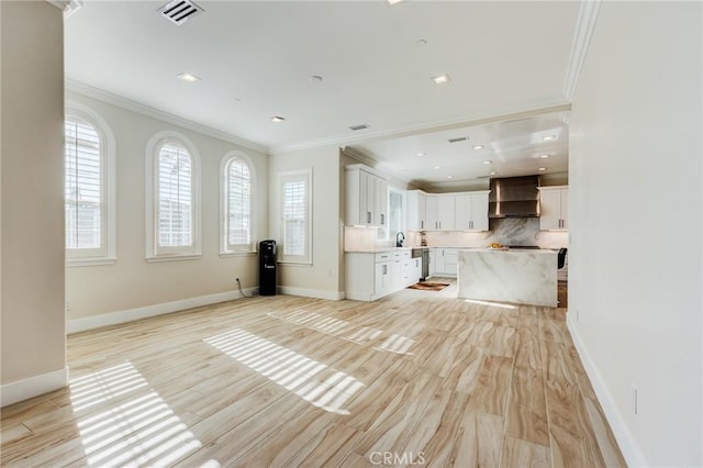 kitchen with white cabinetry, wall chimney exhaust hood, ornamental molding, decorative backsplash, and a kitchen island