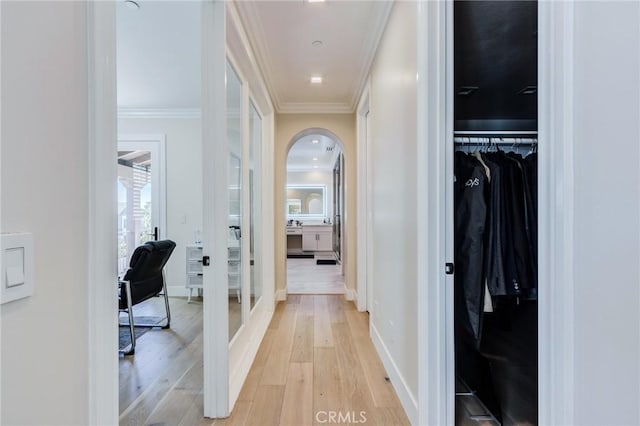 hallway with light wood-type flooring and crown molding