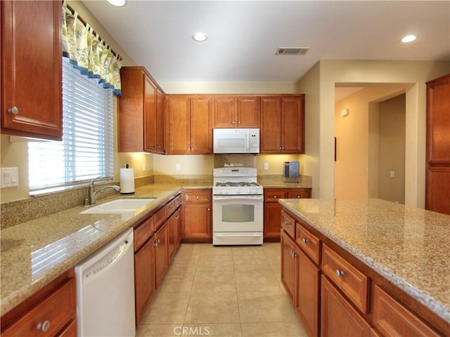 kitchen with light stone counters, sink, white appliances, and light tile patterned floors