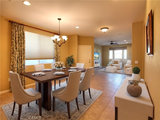 tiled dining space with ceiling fan with notable chandelier