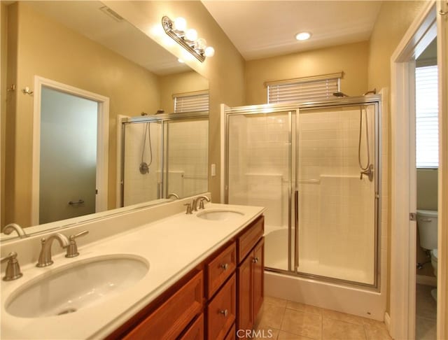 bathroom with toilet, tile patterned flooring, a shower with door, and vanity