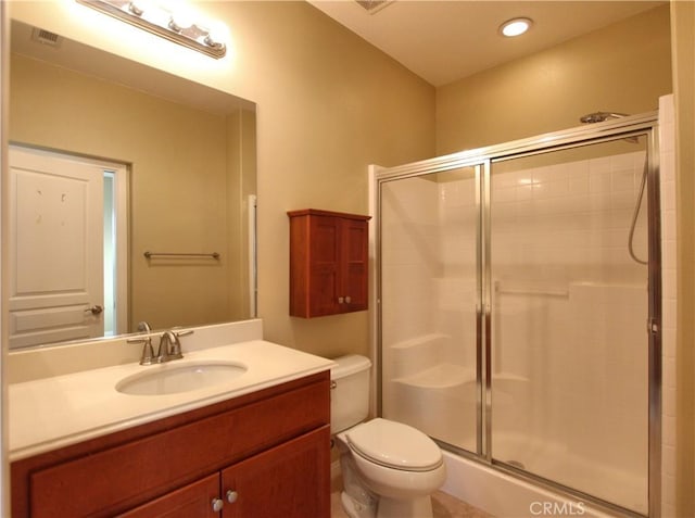 bathroom featuring toilet, vanity, and a shower with door