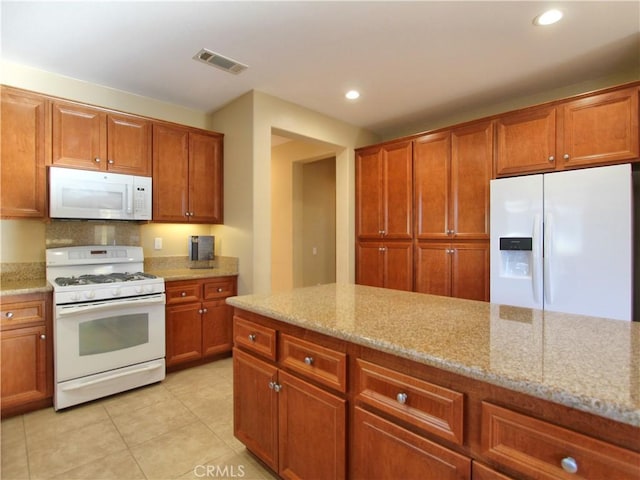 kitchen with light stone counters, white appliances, decorative backsplash, and light tile patterned flooring