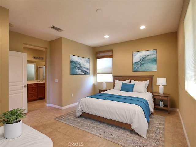 bedroom with ensuite bathroom, light tile patterned floors, and sink