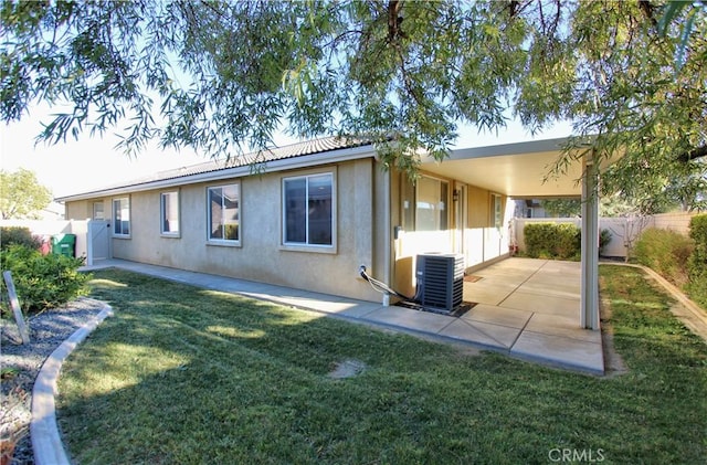 rear view of house with a patio area, central air condition unit, and a yard