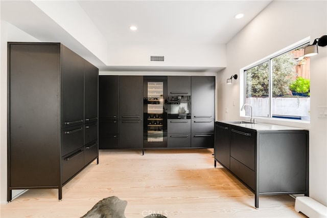 kitchen with light wood-type flooring, sink, and wall oven