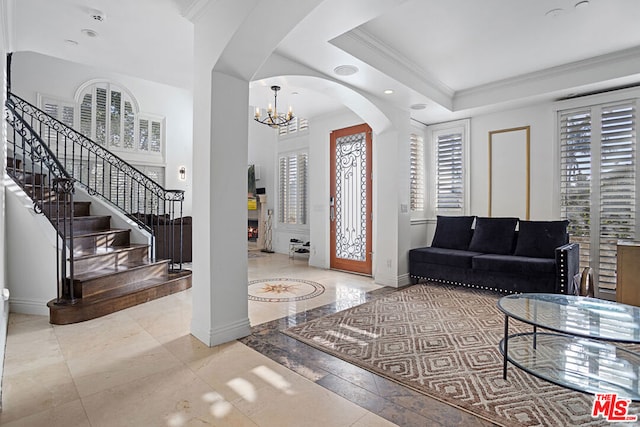 entrance foyer with a raised ceiling, an inviting chandelier, and crown molding