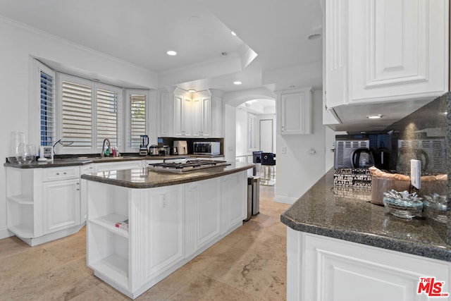 kitchen with white cabinets, appliances with stainless steel finishes, ornamental molding, and a kitchen island