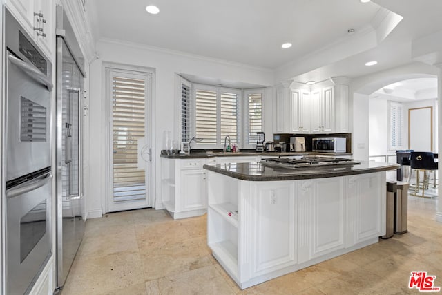 kitchen featuring appliances with stainless steel finishes, white cabinetry, a raised ceiling, and a kitchen island