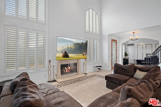 living room featuring a towering ceiling, a wealth of natural light, and a chandelier