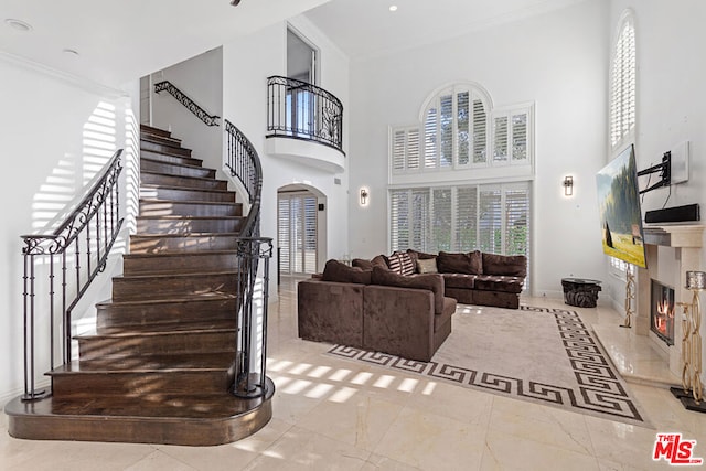 living room with light tile patterned floors, a high ceiling, and ornamental molding