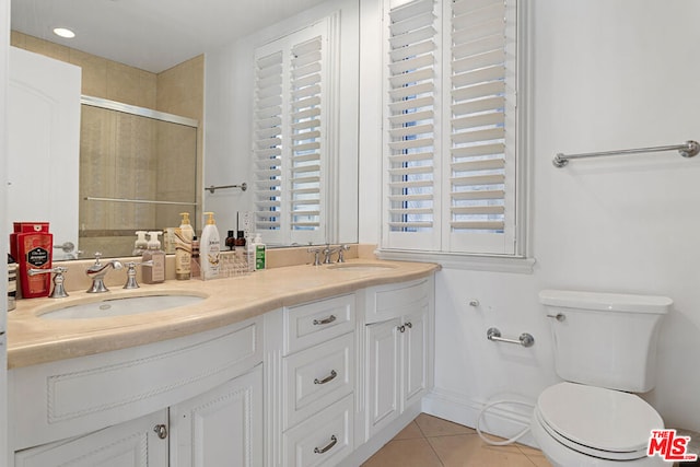 bathroom with toilet, vanity, a shower with door, and tile patterned floors