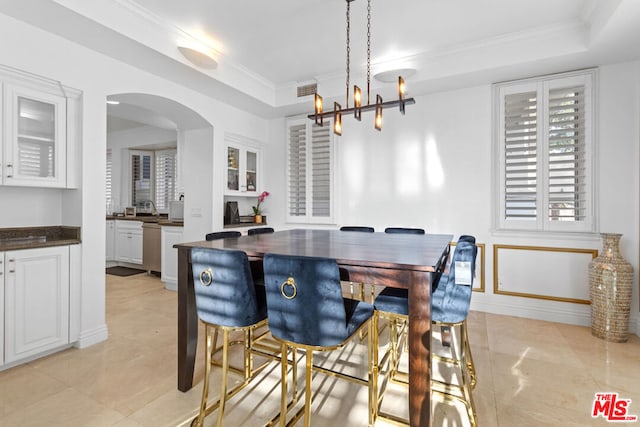 dining area with ornamental molding, a raised ceiling, and a chandelier