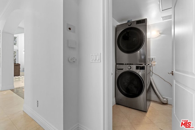 clothes washing area with stacked washer / dryer and light tile patterned floors