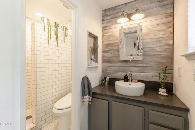 bathroom with vanity, toilet, a shower, and wooden walls