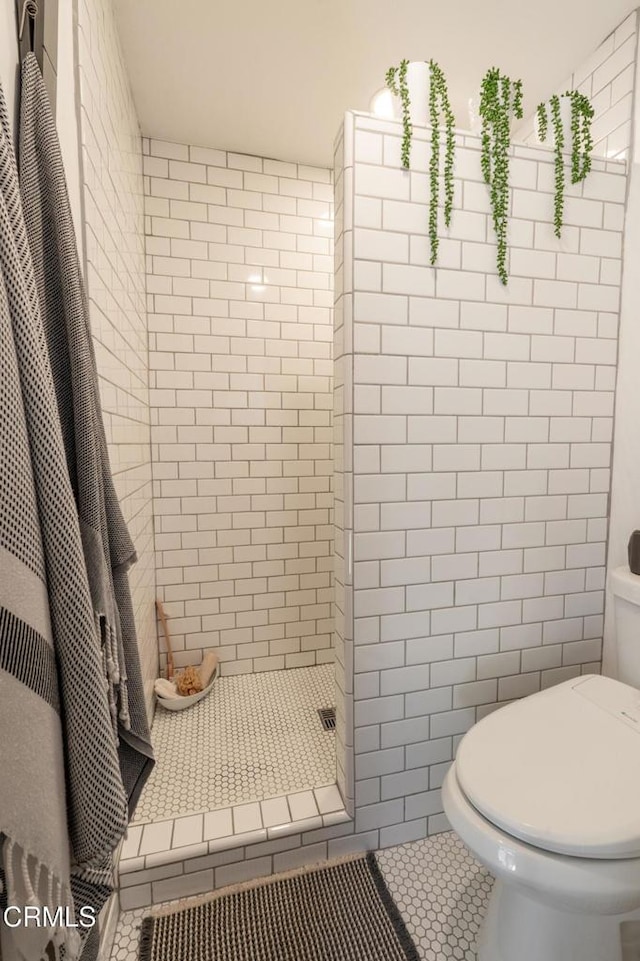 bathroom with a stall shower, toilet, tile patterned flooring, and tile walls