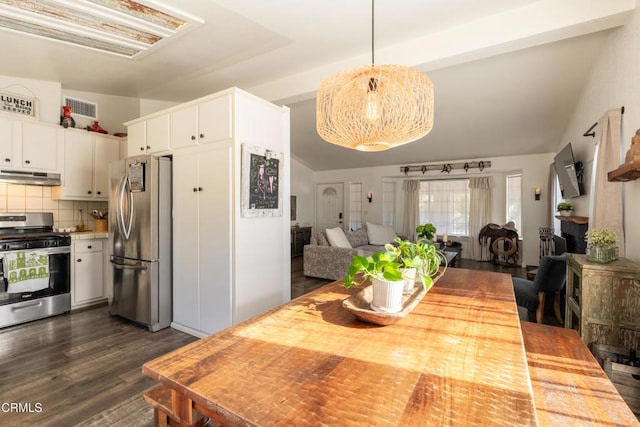 dining area featuring dark wood-type flooring, lofted ceiling, and visible vents