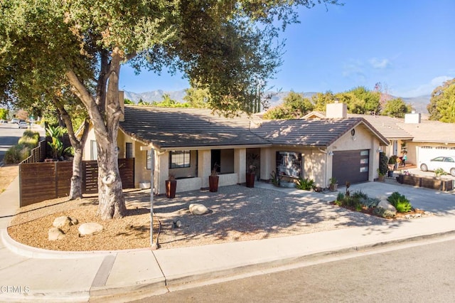 ranch-style house featuring fence, a chimney, a garage, concrete driveway, and stucco siding