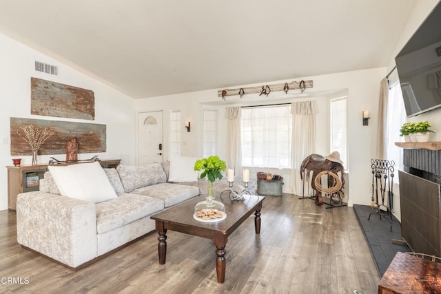 living area featuring vaulted ceiling, visible vents, and wood finished floors