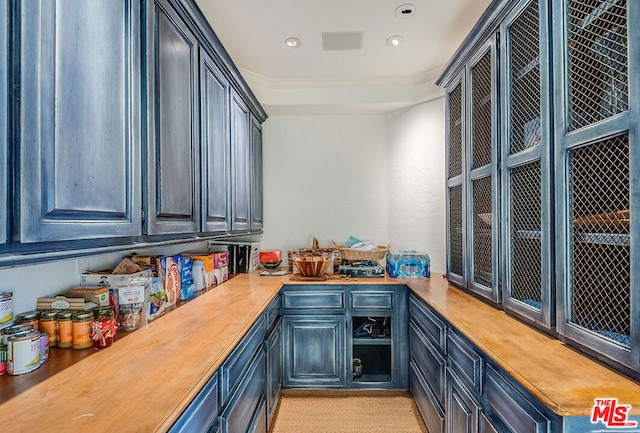 interior space featuring blue cabinetry, butcher block countertops, and crown molding