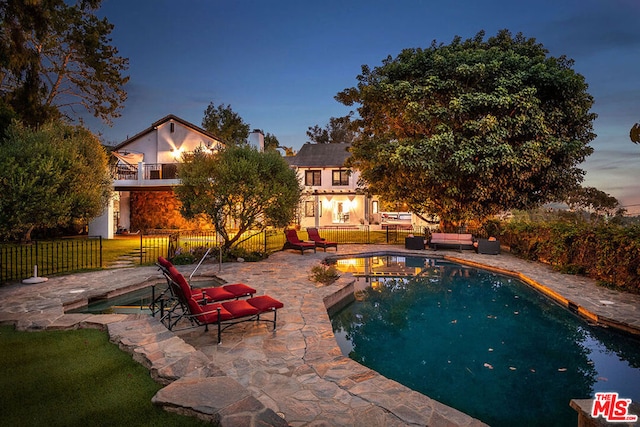 pool at dusk featuring a patio area and outdoor lounge area