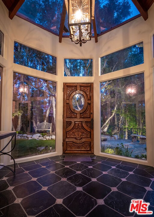 entryway featuring a chandelier, beam ceiling, and high vaulted ceiling