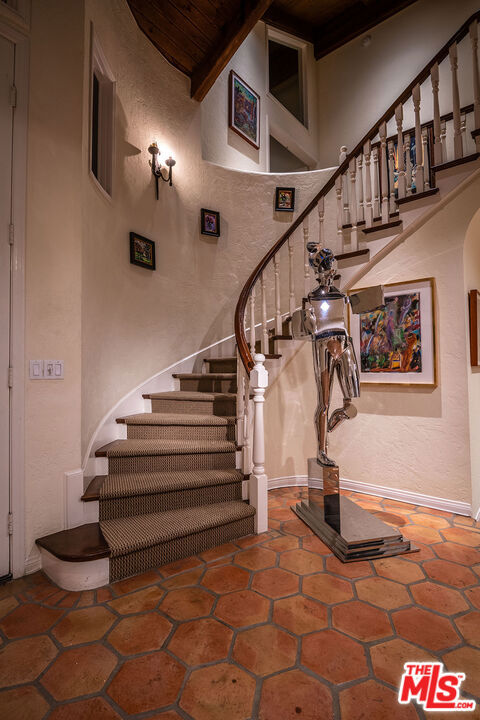 stairway featuring beam ceiling and a high ceiling