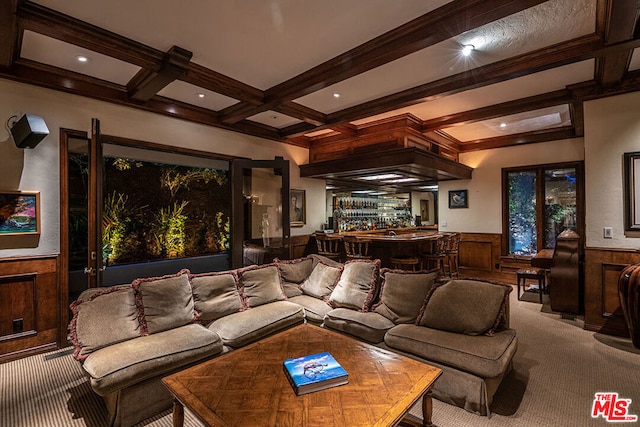 carpeted cinema with beam ceiling, wood walls, bar, and coffered ceiling