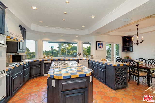 kitchen featuring stainless steel appliances, a raised ceiling, decorative light fixtures, and a center island