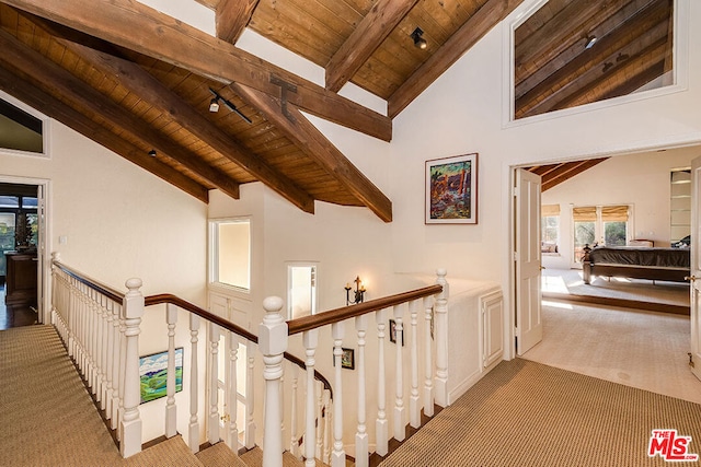 hallway featuring high vaulted ceiling, light colored carpet, wood ceiling, and beamed ceiling