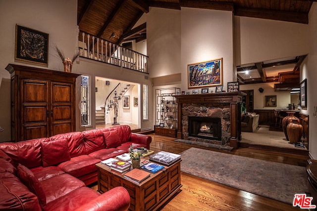 living room with beamed ceiling, a fireplace, light hardwood / wood-style floors, high vaulted ceiling, and wooden ceiling