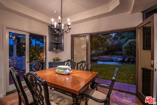 dining area with crown molding, an inviting chandelier, and a tray ceiling