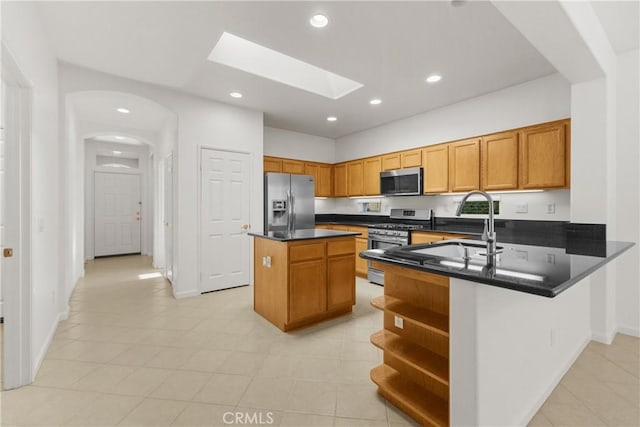 kitchen with a center island, kitchen peninsula, sink, a skylight, and stainless steel appliances